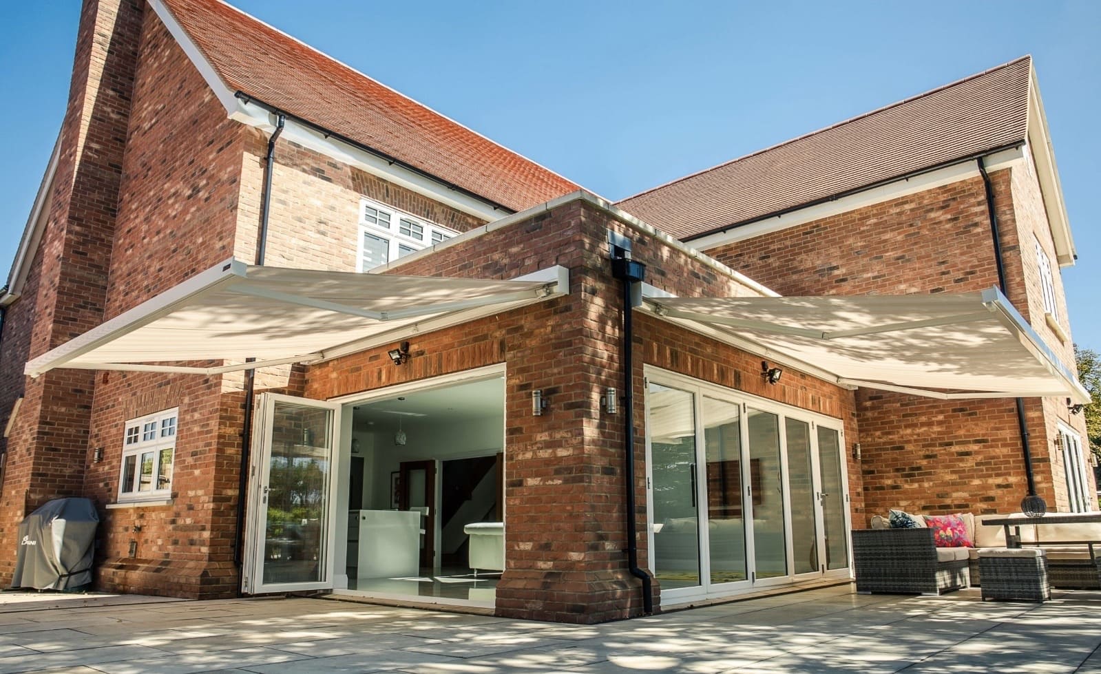 Twin white retractable awnings extended on a large modern brick property