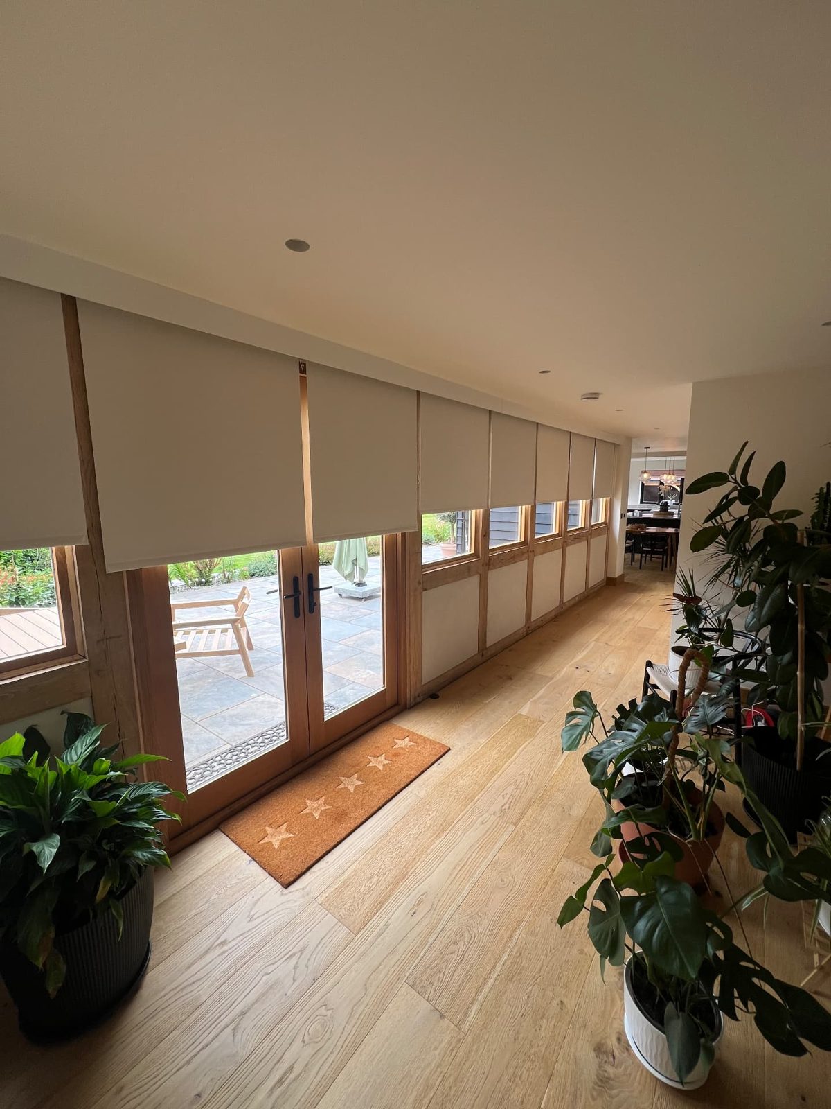 Neutral roller blinds partially lowered on a row of oak-framed doors and windows