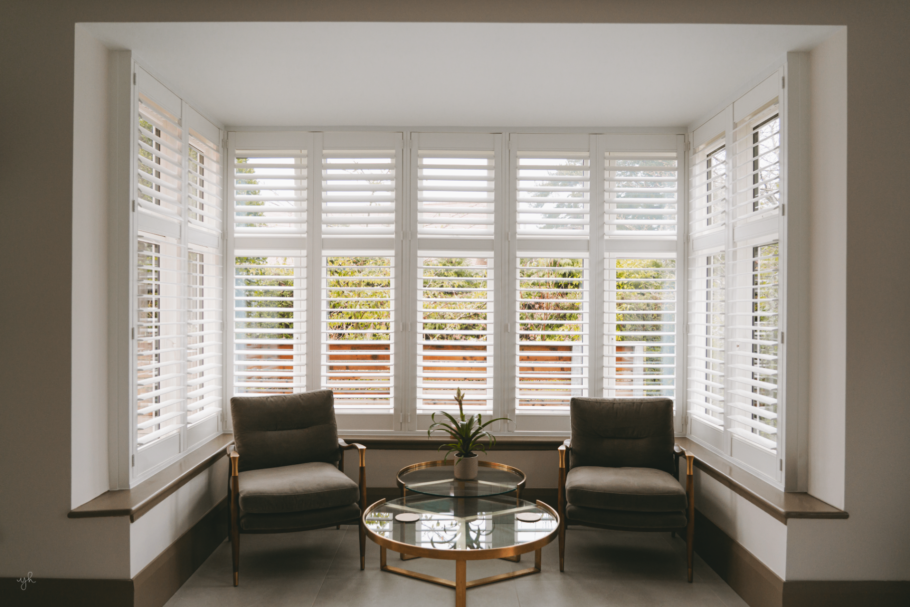 Bay window shutters fitted in a Herefordshire home with two armchairs and a gold coffee table