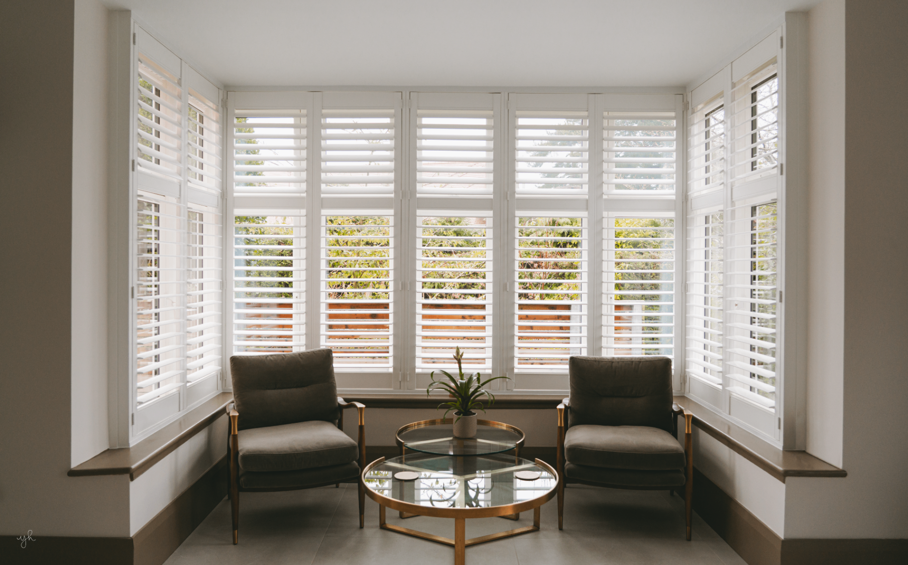 Bay window shutters fitted in a Herefordshire home with two armchairs and a gold coffee table