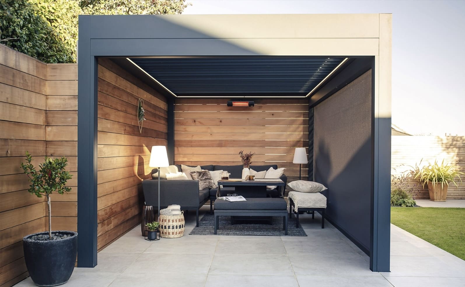 Anthracite louvred pergola at golden hour with outdoor sofa and soft lighting