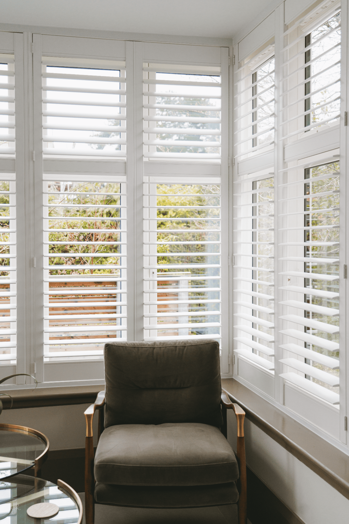 Single armchair beside fitted bay window shutters in a Herefordshire home