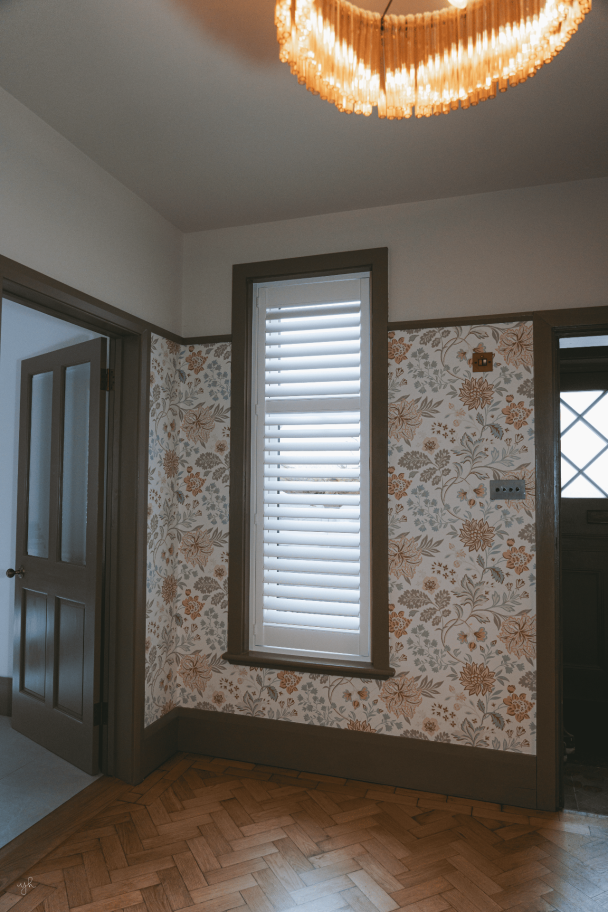 Single white shutter fitted against patterned wallpaper in a period home