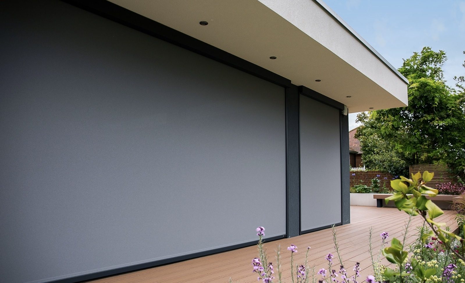 Anthracite exterior zip screens lowered over large glass doors on a modern home